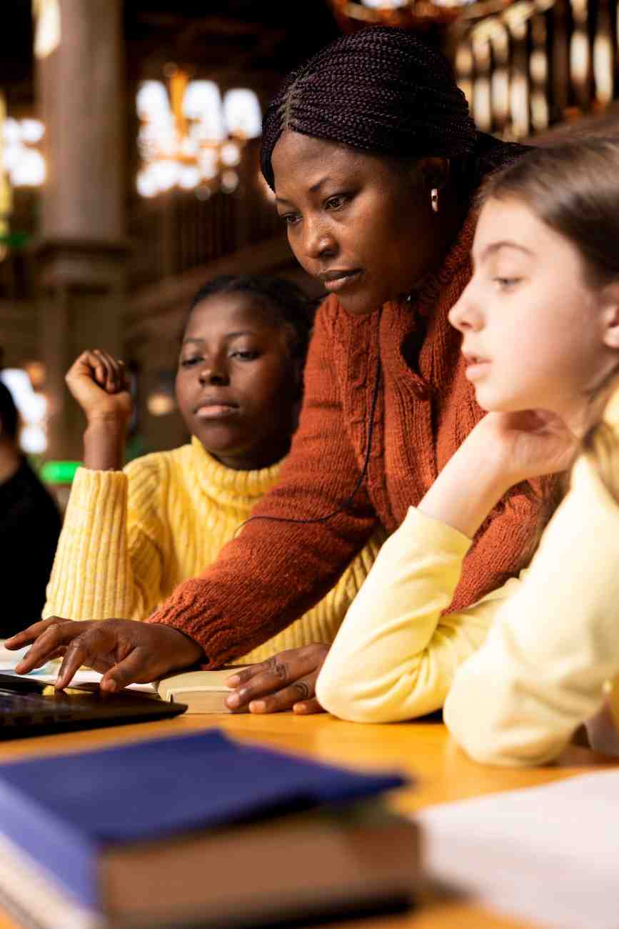 African american professor mentoring a group of diverse students in a library