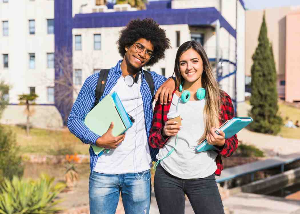 Happy mixed race couple posing in front of a university building