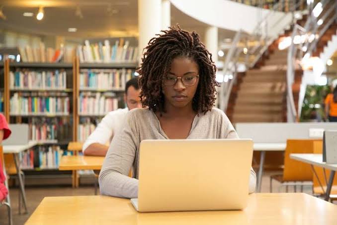 Black woman making use of her laptop in a library